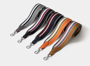 Close up view of colorful woven wide bag straps with leather ends and silver metal hooks.
