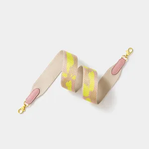 Wide canvas bag strap with leather ends and gold tone swivel hooks for crossbody bags.