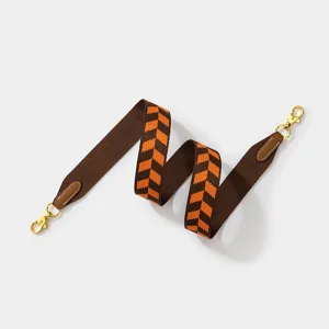 Wide woven bag strap in brown and orange chevron pattern with gold metal clasps for crossbody.
