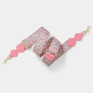 Adjustable wide replacement bag strap with pink patterned webbing and gold hardware.