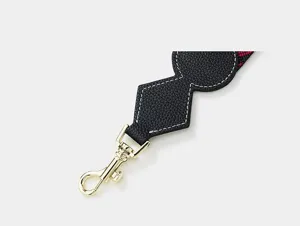 Detailed view of black leather replacement bag strap with gold clasp and clover motif.