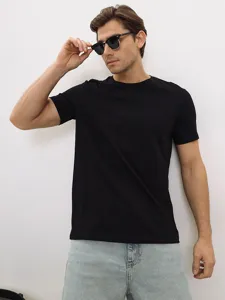 Inquadratura di dettaglio della t-shirt nera a maniche corte classica indossata.