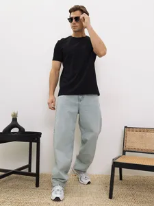 Maglietta da uomo tinta unita a maniche corte abbinata a jeans azzurri per un look casual.