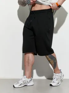 Detailed shot of men's casual athletic shorts, black loose fit sportswear bermuda.
