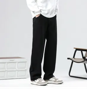 Close-up view of casual loose straight wide-leg black jeans styled in a modern studio setup.