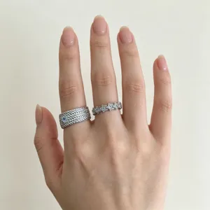 Gros plan détaillé d'une bague tressée en argent et d'un anneau de cristaux étoilés.