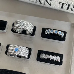 Vue détaillée de bagues empilables tressées et en étoile en argent avec des pierres bleues.