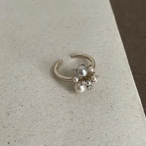 Close-up detail of the elegant pearl cluster open ring, featuring golden band and sparkling stones.