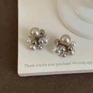 Detailed close-up of French chic cluster pearl earrings with metallic beads and sparkling zircons.