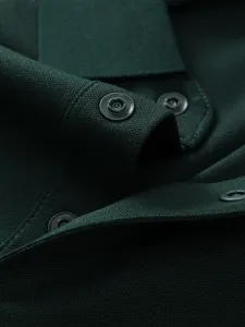 Close-up detail shot showing the premium dark green cotton polo shirt collar and snap buttons.