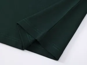 Detail view of dark green mens cotton polo shirt hem showing fine stitching and fabric texture.