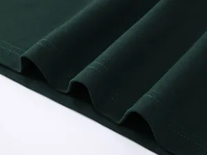 Close-up detail of dark green cotton polo shirt fabric showing fine knit texture and neat stitching.