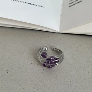 Close-up van een stijlvolle zilverkleurige ring met meerdere strengen en paarse natuurstenen.