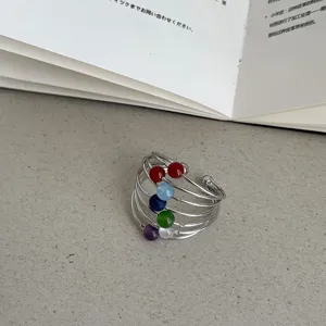 Detailopname van een meerlaagse gewikkelde draadring met kleurrijke natuurstenen kralen.