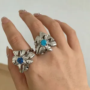 Nahaufnahme von silbernen Blumen-Statement-Ringen mit bunten Kristallkernen an der Hand.