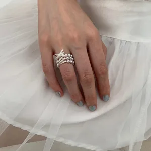 Detailed close-up of the multi-layer pearl ring with sparkling bow accent worn gracefully on finger.