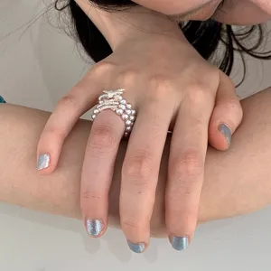 Detail shot of the multi-layer pearl ring featuring a sparkling diamond bow and elastic band.