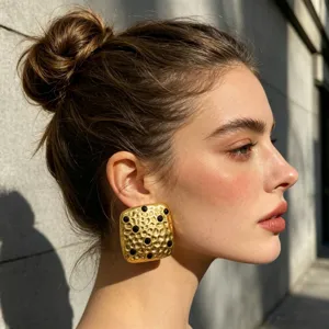 Grote gouden geometrische getextureerde statement oorbellen met zwarte steendetails.