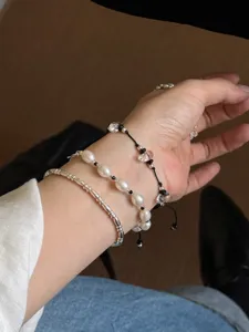 Detailed close-up of a delicate three-piece crystal and pearl bracelet set worn on wrist.