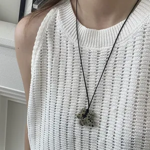 Elegante collana con pendente a fiore in pietra naturale su un cordino nero elegante.