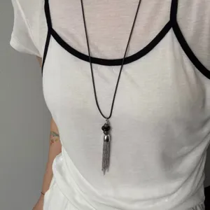 Bella lunga collana con nappina in metallo e cordino di cuoio nero per donne dettaglio.