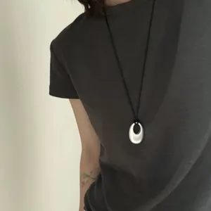 Collana lunga minimalista con ciondolo metallico unico e cordino nero per le donne.