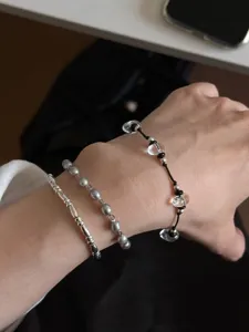Detailed shot of three-piece crystal pearl and silver bead bracelet set worn on wrist.