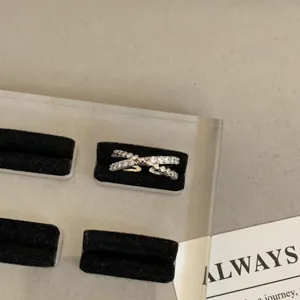 Detailopname van een minimalistische zilveren kruisring bezet met sprankelende zirkonia.