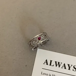 Close-up detail van vintage zilverkleurige opengewerkte ring met rode hart zirkoon.