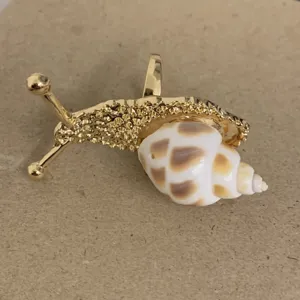 Vergulde slakvormige ring met uniek natuurlijk schelpontwerp. Modieus detailstuk.