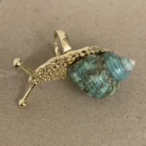 Detailopname van vergulde slakkenring met een uniek blauw schelpontwerp voor dames.