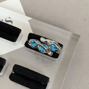 Detail shot of a Y2K blue zircon open ring with abstract silver metal fluid design.