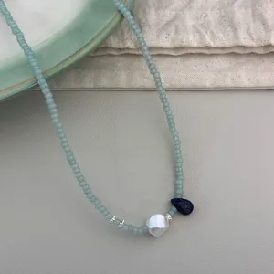 Gros plan sur le collier de perles vert menthe avec perle baroque et pendentif lapis.