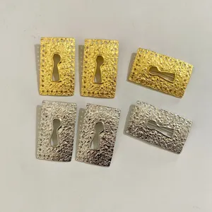 Detailed close-up of retro metallic keyhole earrings with hammered texture in gold and silver.
