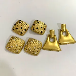 Goudkleurige gestructureerde vierkante oorbellen en geometrische hangende oorbellen.
