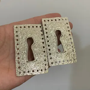 Detailed close-up of vintage metal textured square keyhole drop earrings, chic statement jewelry.