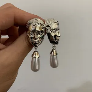 Retro surrealistische metalen gezicht hangende oorbellen met elegante parelhangers.