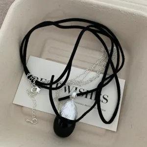 Vista dettagliata della collana unica in corda di velluto nero e catena in argento con ciondolo.