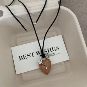 Collana con ciondolo a lucchetto a cuore in legno con chiave e stella su corda nera dettaglio.