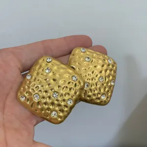 Goudkleurige gestructureerde vierkante statement oorbellen met schitterende strass details.
