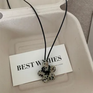 Primo piano dettagliato della collana con ciondolo floreale dal design unico con corda.