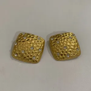 Gedetailleerd overzicht van gouden geometrische oorbellen met strass en gehamerd design.