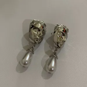Gedetailleerde close-up van retro zilveren metalen gezichtsculptuur oorbellen met parels.