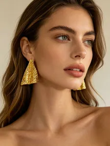 Gedetailleerde close-up van getextureerde onregelmatige gouden oorbellen gedragen.
