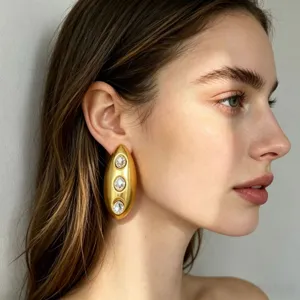 Gouden statement oorbellen met ovaal geometrisch ontwerp en schitterende strass steentjes.