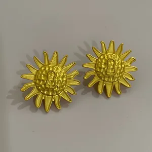 Close-up detail van vintage gouden zonnebloem oorbellen met uniek sleutelgat ontwerp.