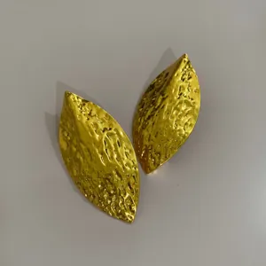 Gouden gestructureerde blad oorknopjes detailweergave, metalen organische mode sieraden.