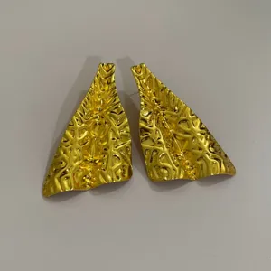 Detailopname van onregelmatige geometrische gouden metalen oorbellen, statement.