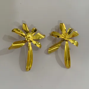 Gedetailleerde close-up van gouden metalen bloem oorbellen, opvallend en stijlvol damesontwerp.