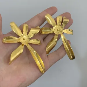 Gouden metaal bloem oorringen detail opname, overdreven bloem ontwerp mode sieraden.